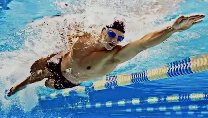 Olahraga Renang Seorang atlet renang meluncur dengan kuat di bawah air, menunjukkan teknik gaya bebas yang sempurna dalam kompetisi renang